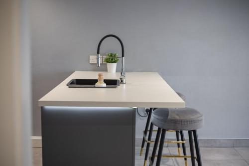 a kitchen with a sink and a counter with stools at #4 Stylish City Centre Apartment with Free Private Parking, close to Hull New Theatre and Connexin Live Arena in Hull
