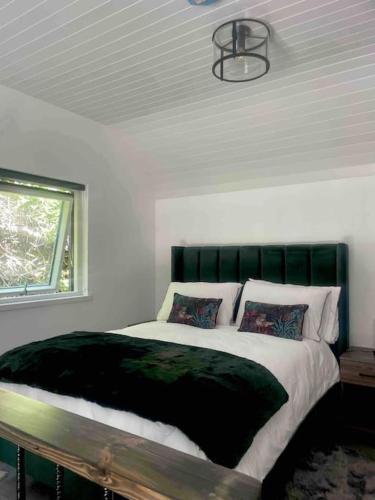 Schlafzimmer mit einem Bett mit einem grünen Kopfteil und einem Fenster in der Unterkunft Railway cottage Annascaul in Anascaul