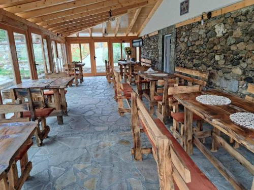 un restaurante con mesas y sillas de madera y una pared de piedra. en MERAK STD en Vranje