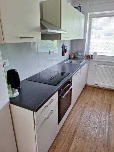a kitchen with white cabinets and a black counter top at Guesthouse Flower in Ljubljana