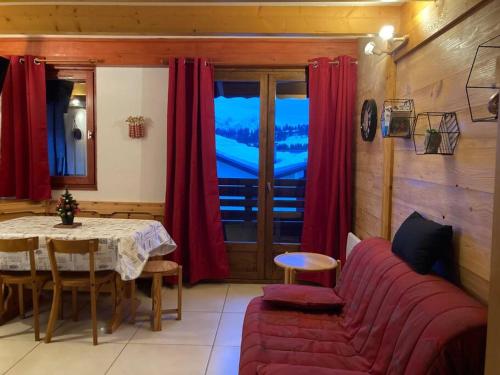 un salon avec un canapé rouge et une table dans l'établissement Les Saisies Appartement 6 8 personnes en plein centre avec 1 chambre et 2 espaces sous pentes non fermés - Remontées mécaniques à 200 m, à Hauteluce