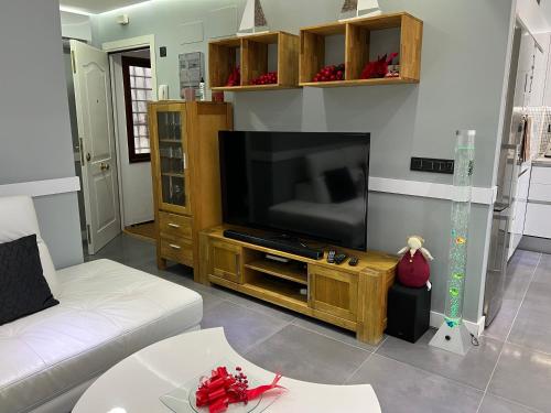 sala de estar con TV y sofá blanco en Apartamento Victorio Las Canteras, en Las Palmas de Gran Canaria