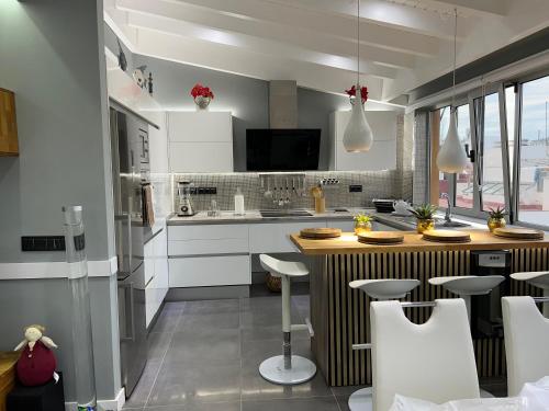 una cocina con armarios blancos y una barra con taburetes en Apartamento Victorio Las Canteras, en Las Palmas de Gran Canaria