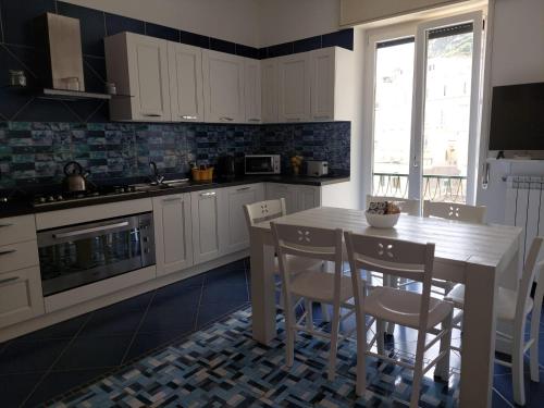 a kitchen with white cabinets and a table and chairs at Blue's House in Atrani