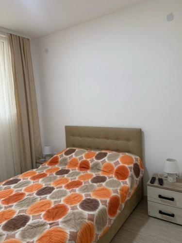 ein Schlafzimmer mit einem Bett mit einer orange-grauen Bettdecke in der Unterkunft City Dream in Sokobanja