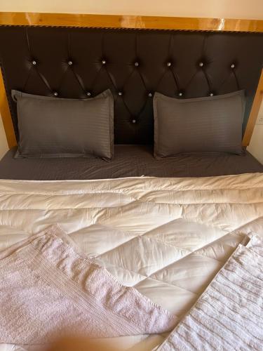 a bed with a black headboard and white sheets and pillows at Sky Land guest house in Leh