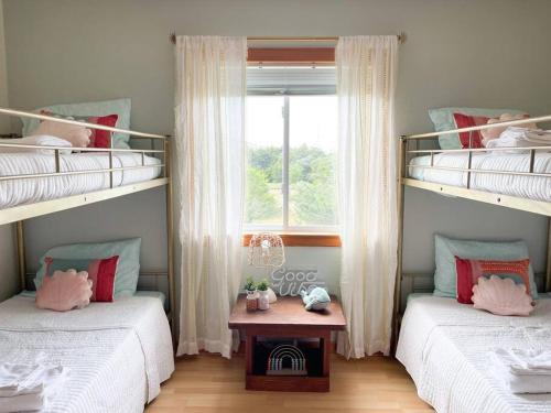 two bunk beds in a room with a window at The Lost Loggerhead- OBX Ocean view Beach House in Avon