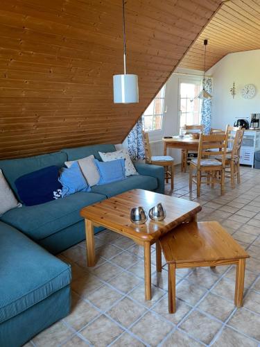 uma sala de estar com um sofá azul e uma mesa em Ferienwohnung direkt am Deich - Seerobbe - em Dornum