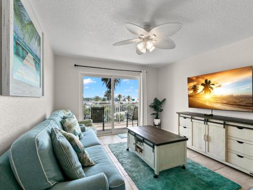 a living room with a blue couch and a tv at Madeira Norte 304 in St Pete Beach