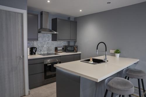 a kitchen with a sink and a counter with stools at #4 Stylish City Centre Apartment with Free Private Parking, close to Hull New Theatre and Connexin Live Arena in Hull