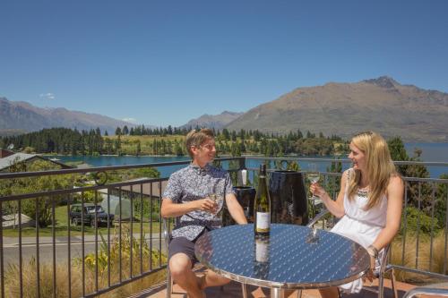 a man and a woman sitting at a table with wine glasses at Alexis Motel & Apartments in Queenstown