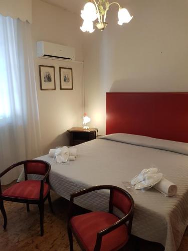 a bedroom with a bed with two chairs and a table at Hotel Villa Pagoda in Sirmione