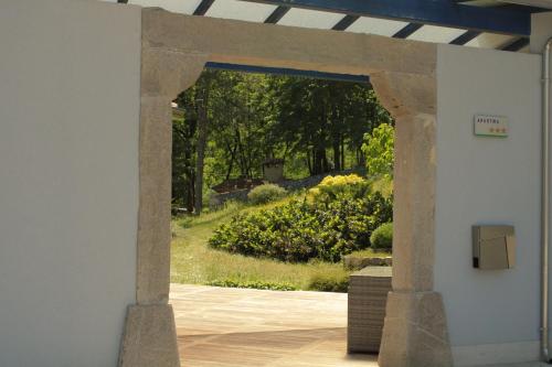 vista su un giardino attraverso un arco in pietra di Apartment Dandelion a Branik