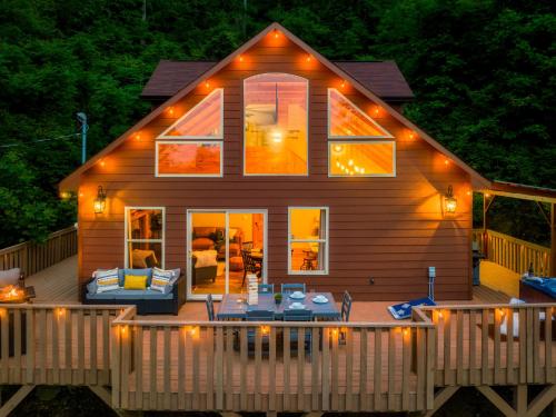 uma casa com um deque com uma mesa e cadeiras em Mountainside - New Luxury Cabin-Fire Table-Hot Tub-3 Pools-PS5-Bears em Gatlinburg