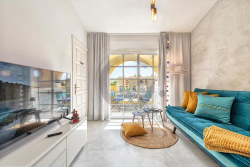 un salon avec un canapé bleu et une télévision dans l'établissement Tisalaya Bright Apartment, à Maspalomas