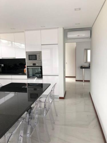 a kitchen with white cabinets and a counter with chairs at Villa - Âncora - 300 mètres de l’océan in Vila Praia de Âncora