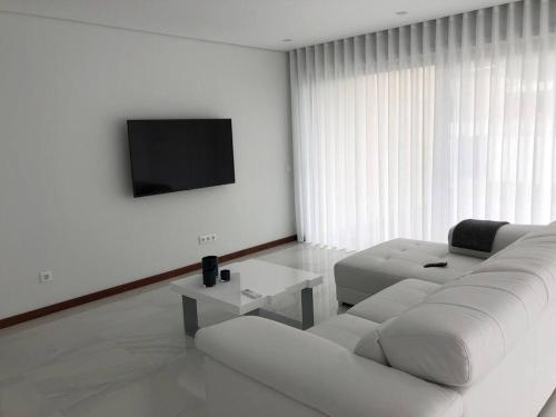 ein weißes Wohnzimmer mit einem weißen Sofa und einem TV in der Unterkunft Villa - Âncora - 300 mètres de l’océan in Vila Praia de Âncora
