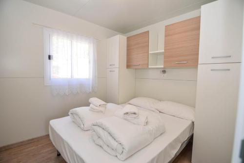 a white room with two beds with towels on them at Mobilhome Camping Azzurro in Ledro