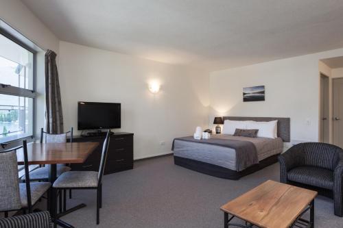 a bedroom with a bed and a table and a television at Alexis Motel & Apartments in Queenstown