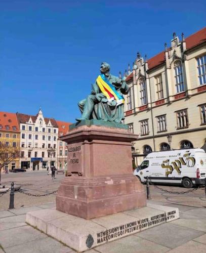 a statue of a man holding a flag in a city at Rynek pod Fredrą in Wrocław