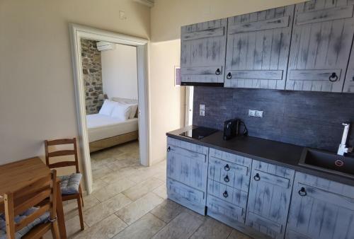 a kitchen with blue cabinets and a table and a bed at Villa Panorama in Iraklia