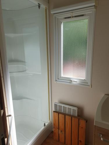 La salle de bains est pourvue d'une douche et d'une fenêtre. dans l'établissement Mobil-home ( dépaysement total à 40 km de paris ), à Saint-Chéron