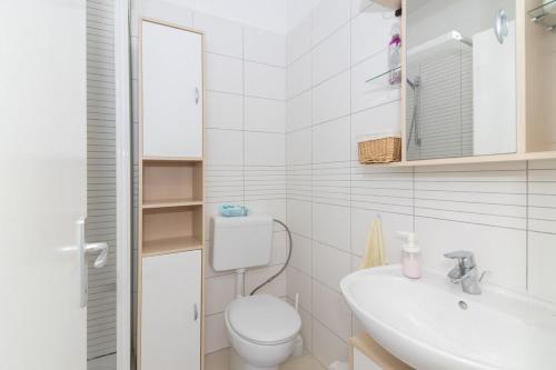 a white bathroom with a toilet and a sink at Apartment Perla in Dinjiška