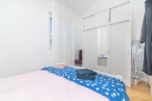 a white bedroom with a bed with a blue blanket at Apartment Perla in Dinjiška