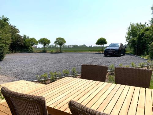 a wooden table with chairs and a car in a parking lot at De Scheure, charmant vakantiehuisje midden in de natuur in Alveringem