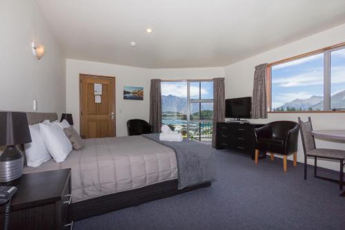 a hotel room with a bed and a desk and window at Alexis Motel & Apartments in Queenstown