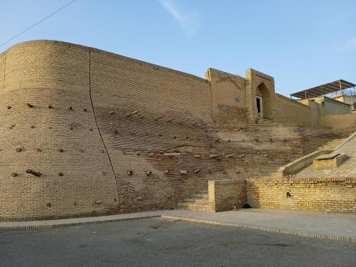 a large brick wall next to a street at Guest House "AN" & Teahouse in Bukhara