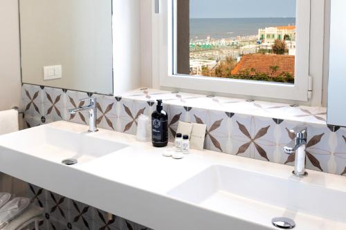 un bagno con due lavandini e un grande specchio di Hotel Cristallo a Senigallia