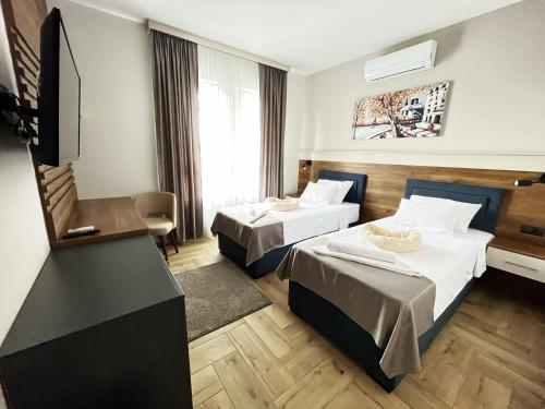 a hotel room with two beds and a flat screen tv at ĆAKA Luxury Rooms & Restaurant in Ćuprija