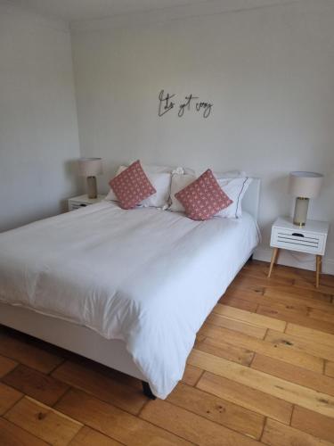 Un dormitorio con una cama blanca con almohadas. en Vimy House, en Clifden