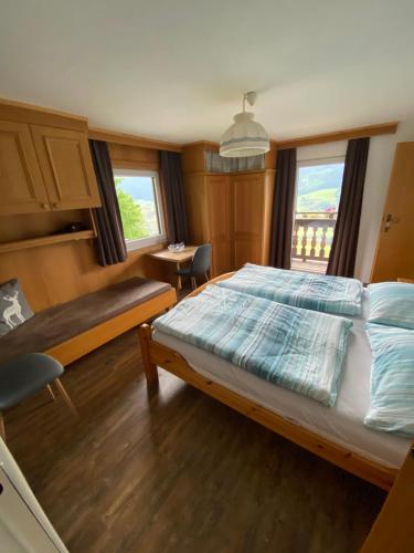 Schlafzimmer mit einem Bett, einem Tisch und Fenstern in der Unterkunft Landhaus Aigner in Mittersill