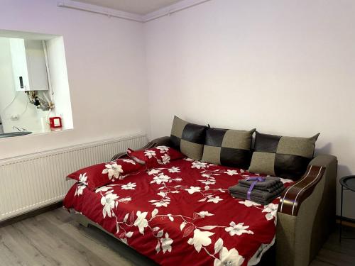 - une chambre avec un lit et une couverture rouge fleurie dans l'établissement Julia Apartament, à Zalău