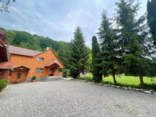 a house with a gravel driveway in front of it at Pensiunea Hétvezér Panzió in Sub Cetate