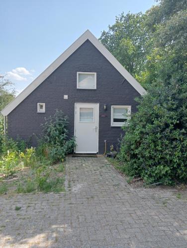 a black house with a white door at Tiny House Aqualinde in Breda