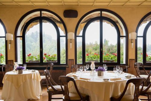 a dining room with tables and chairs and windows at Hotel Villa Cipriani in Asolo
