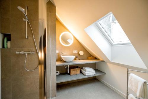 een badkamer met een wastafel en een dakraam bij Bij de secretaris in Kanne