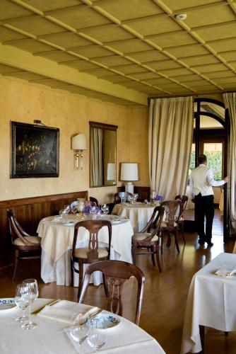 a dining room with white tables and chairs and a person in the background at Hotel Villa Cipriani in Asolo