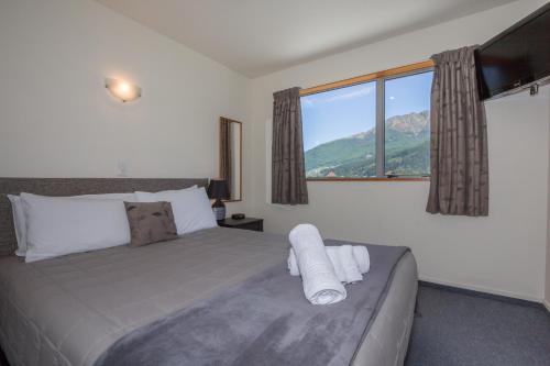 a bedroom with a bed with a large window at Alexis Motel & Apartments in Queenstown