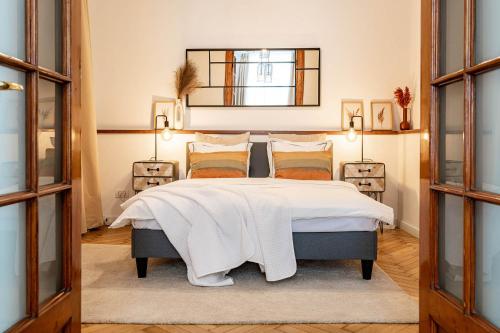 een slaapkamer met een bed met witte lakens en een spiegel bij The- POINT- 3BR Bright Cloud in Boekarest