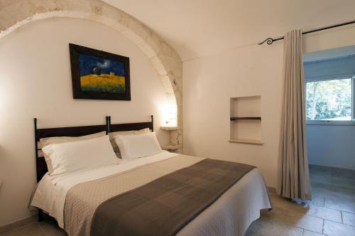 マルティナ・フランカにあるB&B Trulli Valle d'Itriaのベッドルーム1室(ベッド1台付)が備わります。壁には絵画が飾られています。