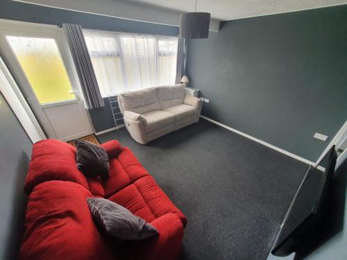 a living room with a red couch and a chair at Hemsby Hideaway in Great Yarmouth