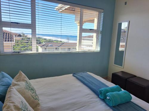 a bedroom with a bed with a view of the ocean at Hello Holiday at 4 Boboyi Mangrove Beach Estate in Port Shepstone