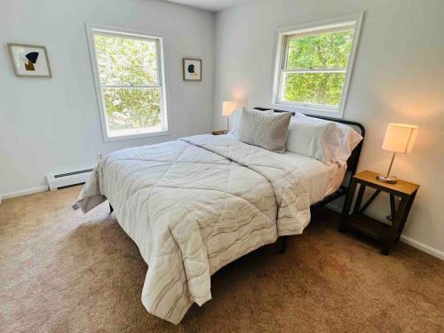 a bedroom with a large bed with two windows at Hamptons Escape: Near Beaches, Restaurants, Wineries. in Hampton Bays