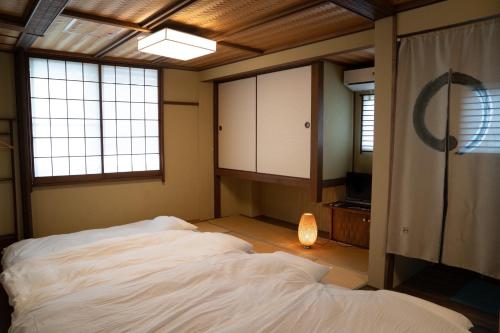a bedroom with a bed in a room with windows at Kyo no Yado Sangen Ninenzaka in Kyoto