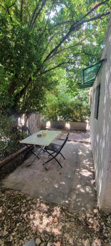 une table de pique-nique assise sous un arbre à côté d'un bâtiment dans l'établissement Studio en camargue, à Arles