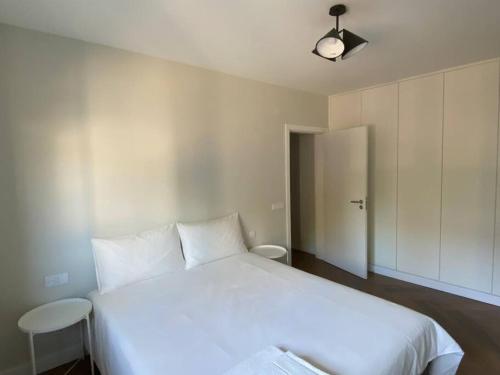 a bedroom with a large white bed with two chairs at Casa com jardim perto da praia in Sesimbra